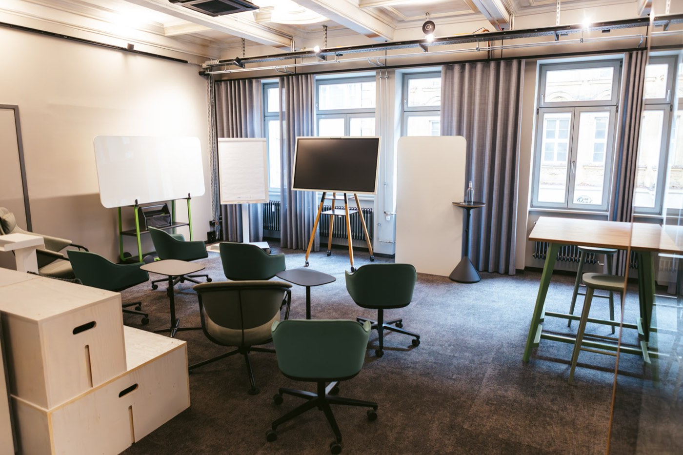 Studio im club199: Sessel-Runde mit Screen, Flipchart und Stehtisch am Fenster